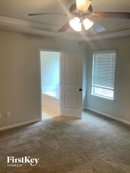 an empty living room with a ceiling fan and a white door