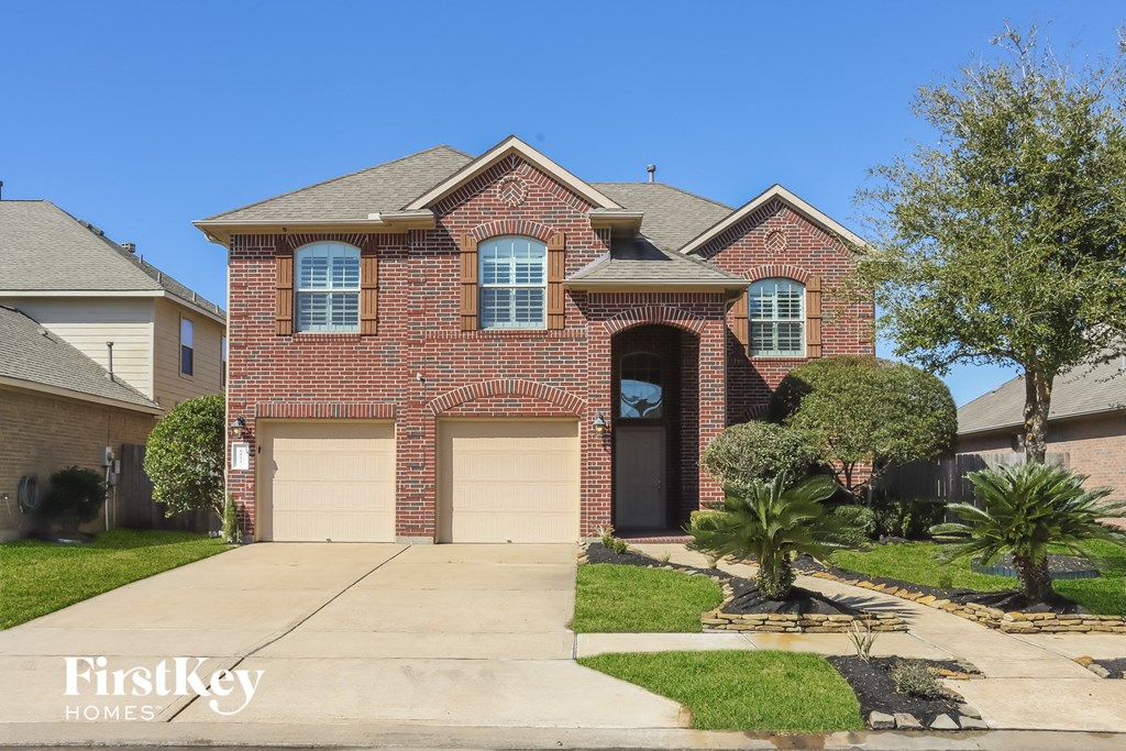 a red brick house with two garage doors and a palm tree