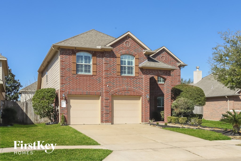 a brick house with two garage doors and a lawn
