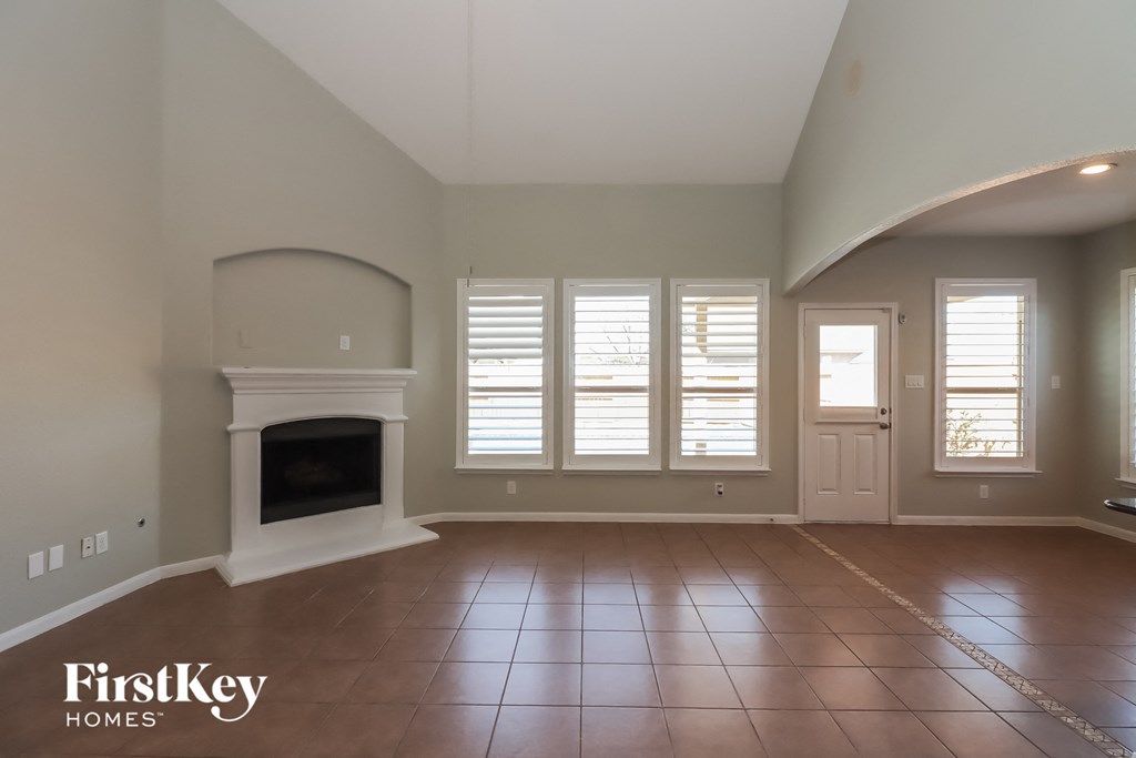 an empty living room with a fireplace and windows