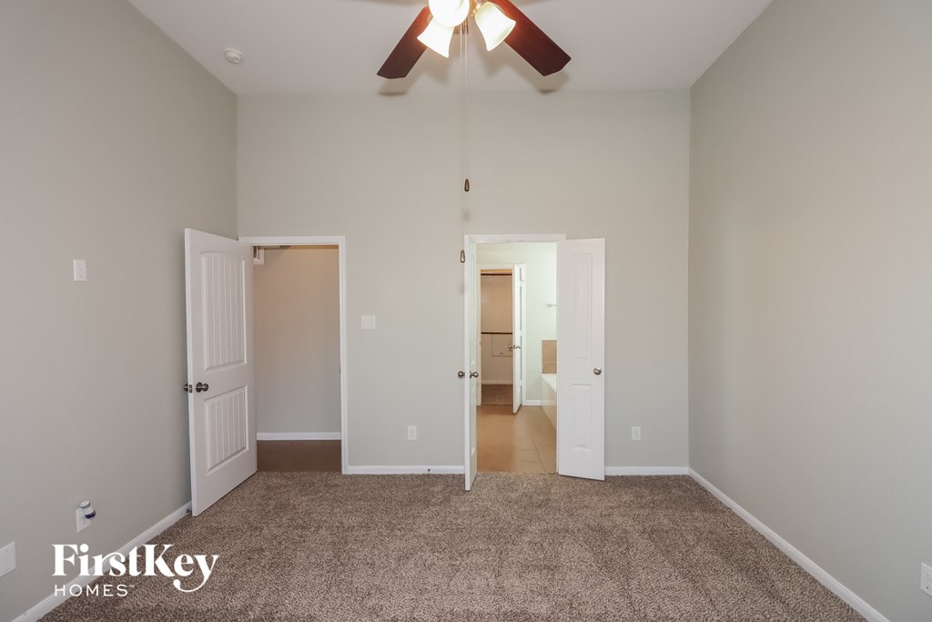 a bedroom with a carpeted floor and a ceiling fan