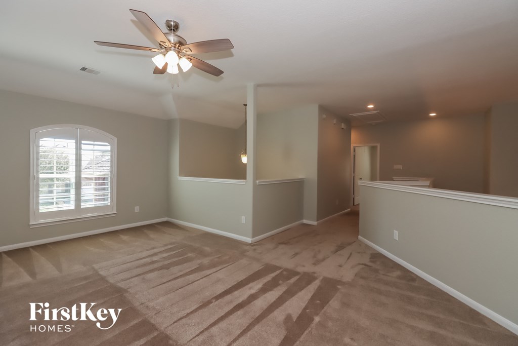 an empty living room with a ceiling fan and a window