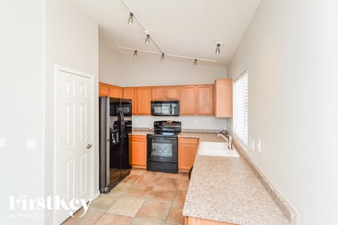 A kitchen with a black oven and orange cabinets.