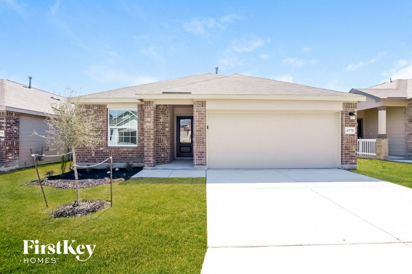 A house with a garage and a tree in front of it.