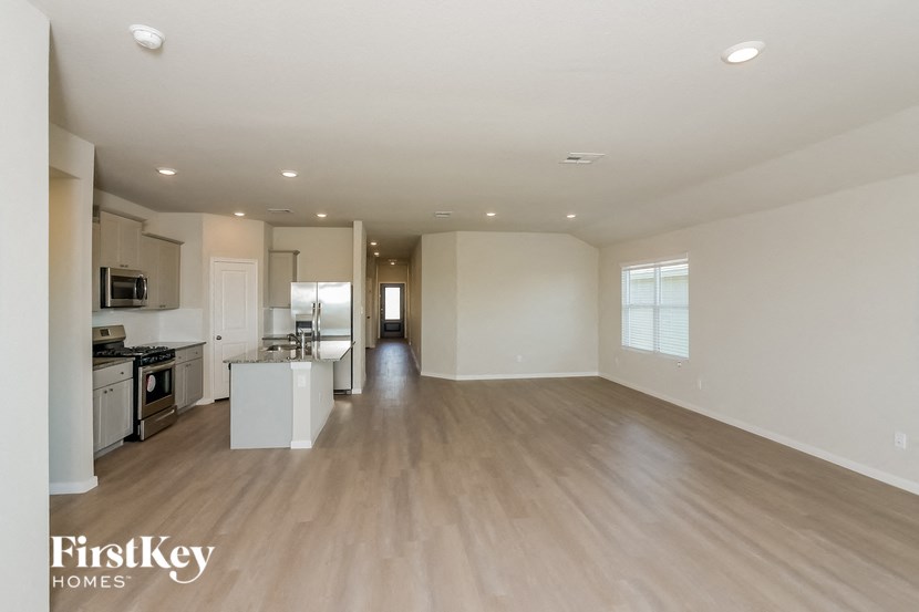 A spacious empty room with wooden flooring and white walls.