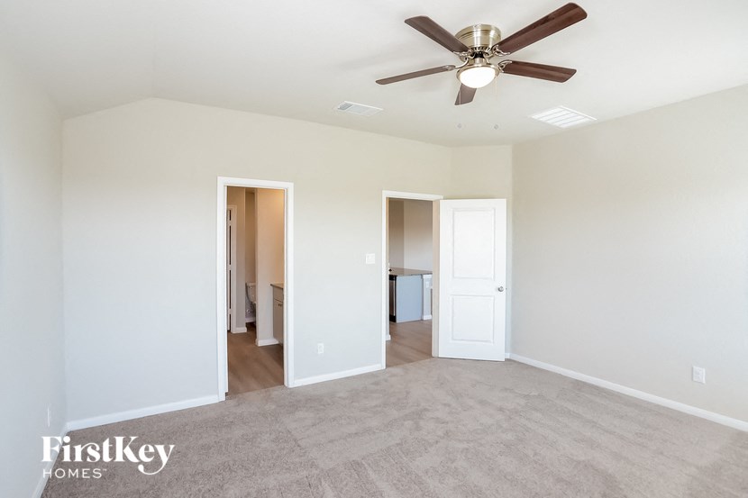 A spacious room with a ceiling fan and two doors.