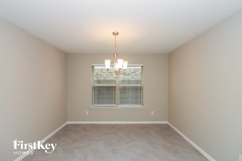 a empty dining room with a window and a chandelier