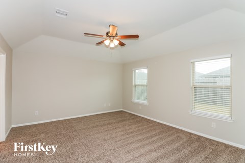 a living room with a ceiling fan and a carpet