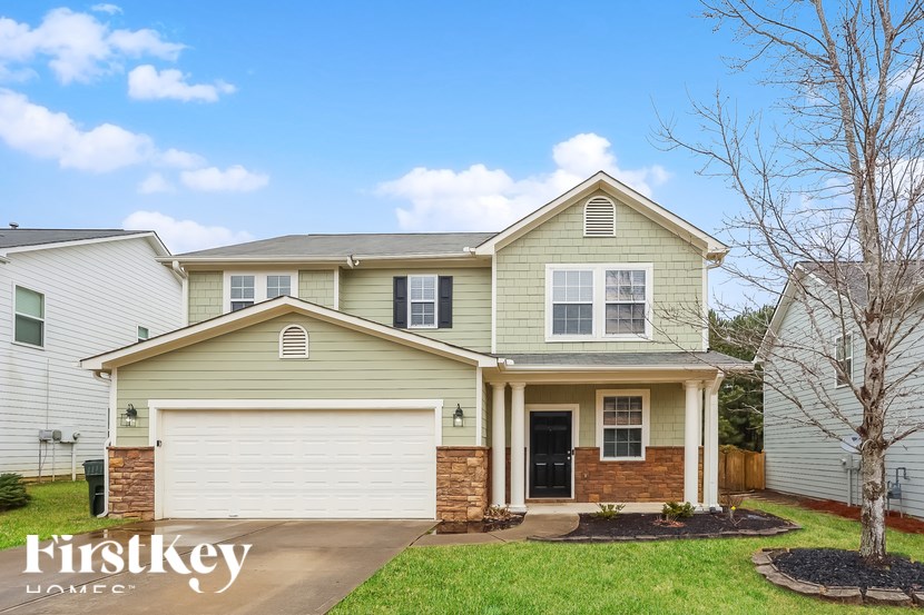 A house with a garage and a tree in front of it.