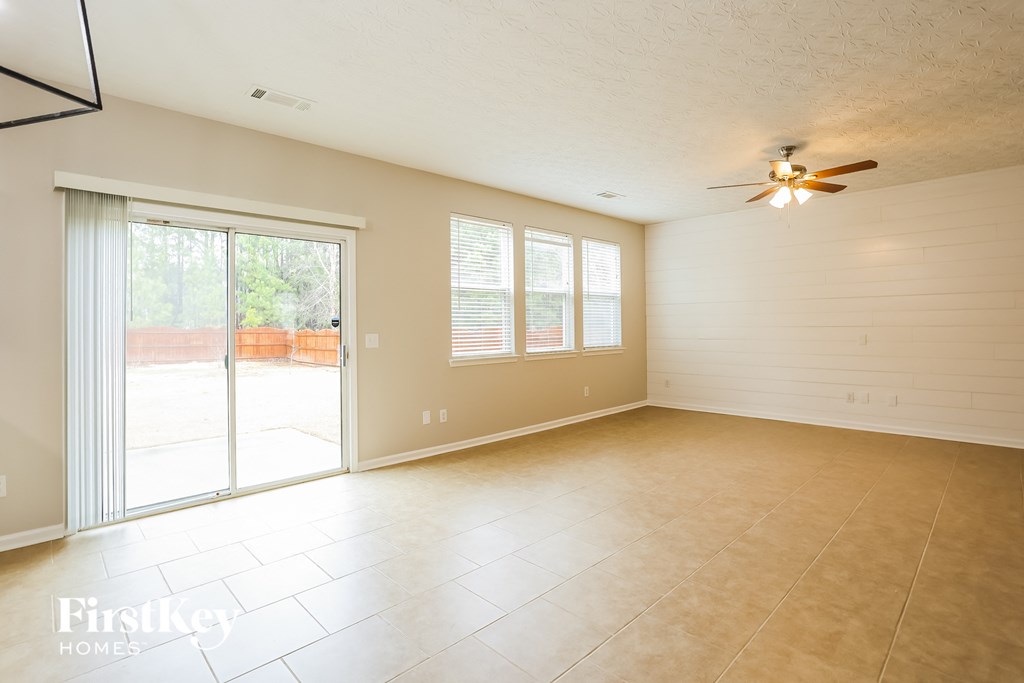 A spacious room with a ceiling fan and sliding glass doors.