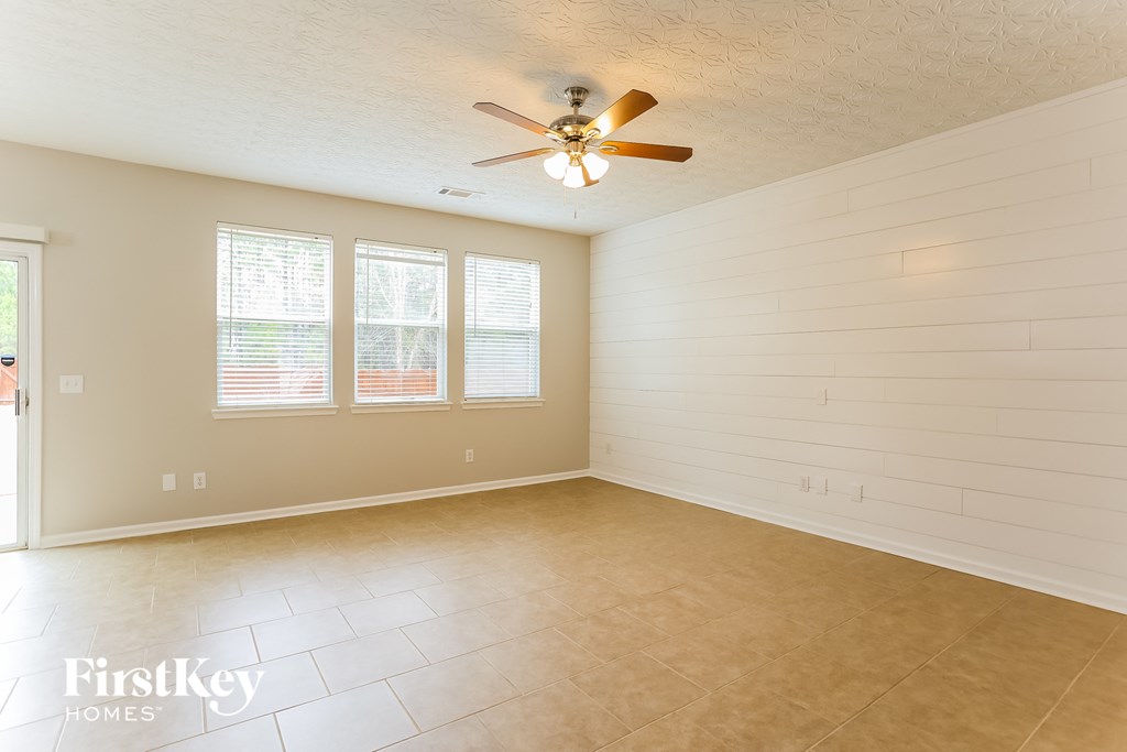 A spacious room with a ceiling fan and three windows.