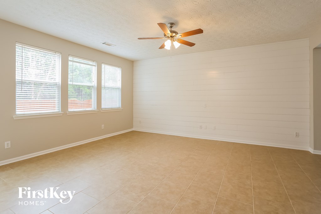 A spacious room with a ceiling fan and three windows.