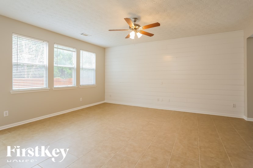A room with a ceiling fan and three windows.