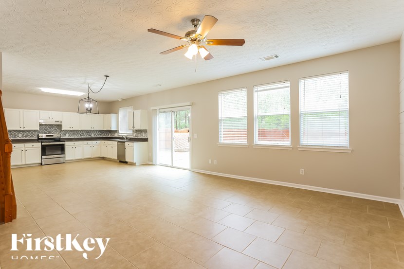A spacious kitchen and living room with a ceiling fan and tiled flooring.