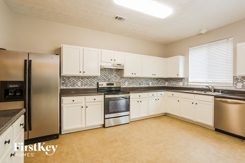 A kitchen with a stainless steel refrigerator and white cabinets.