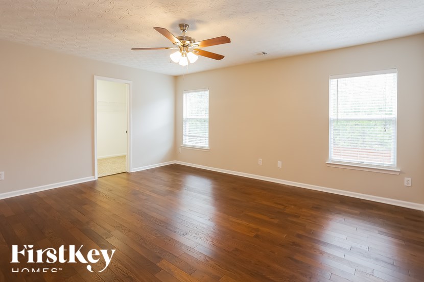 A room with a ceiling fan and wooden floors.
