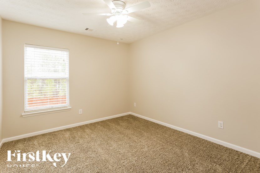 A room with a carpeted floor and a ceiling fan.