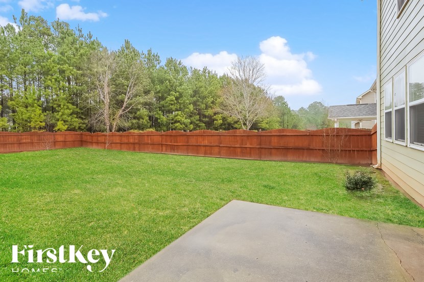 A backyard with a wooden fence and a concrete slab.