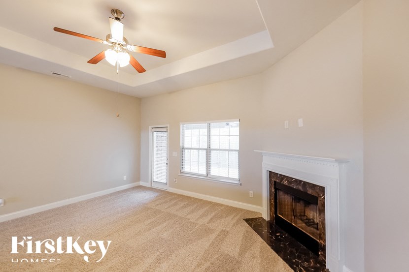 A spacious room with a fireplace and a ceiling fan.