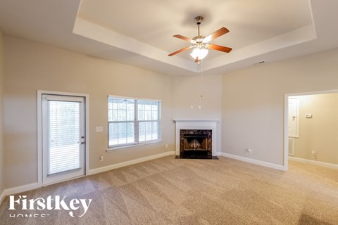 A spacious living room with a fireplace and a ceiling fan.