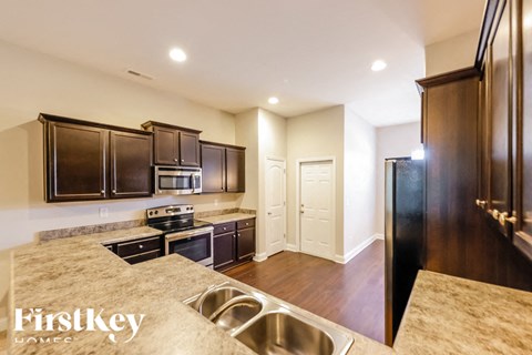 A kitchen with dark wood cabinets and a stainless steel sink.