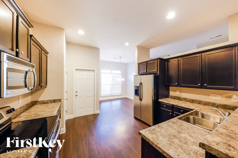 A kitchen with a stainless steel refrigerator and wooden floors.
