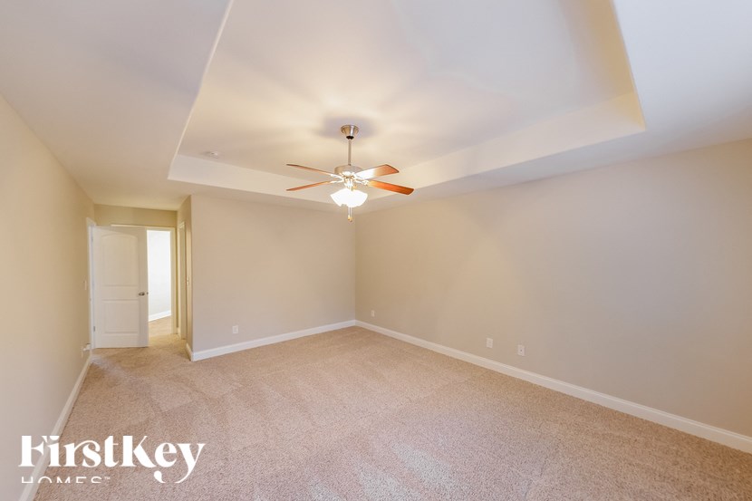 A room with a ceiling fan and carpeted floor.