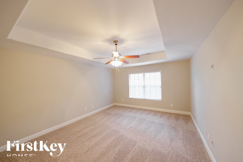 A spacious room with a ceiling fan and a window.