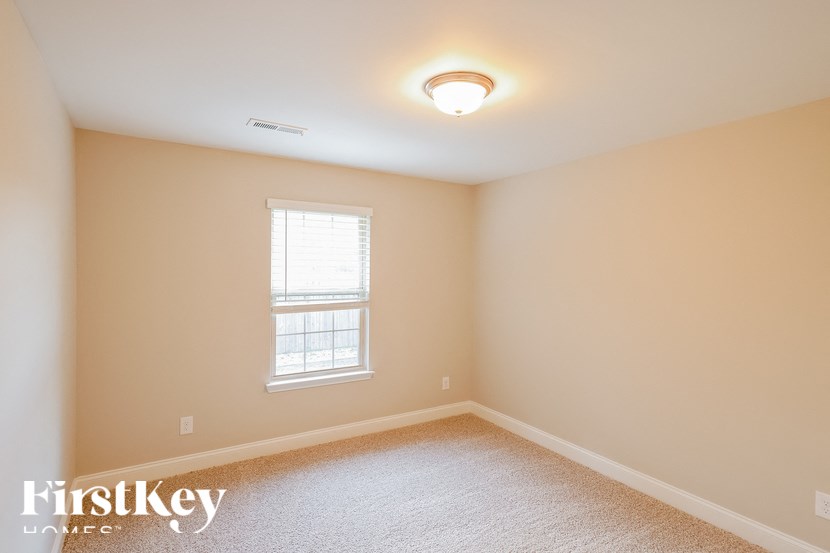 A room with a window and a carpeted floor.