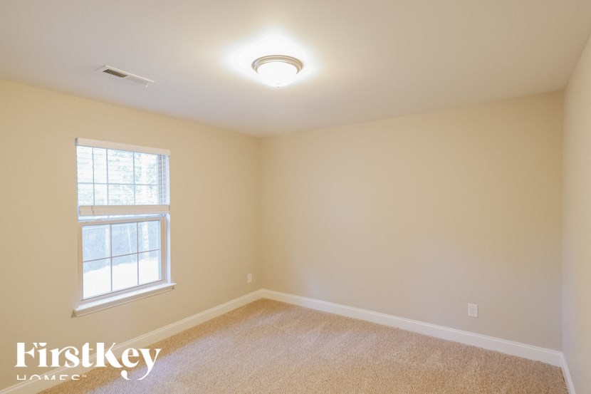 A room with a window and a carpeted floor.