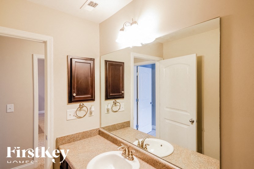 A bathroom with a mirror, sink, and a white door.