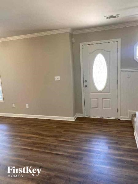 an empty living room with a white door and wood floors