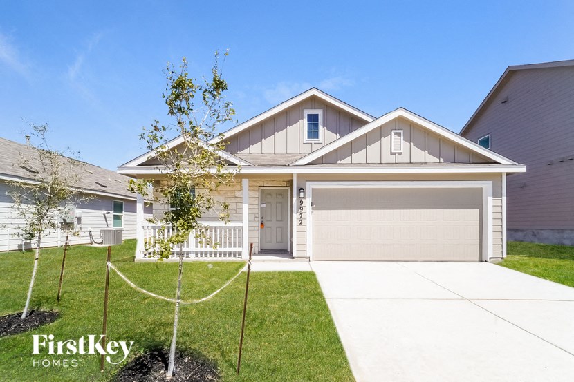 a home with a tree in the front yard and a driveway