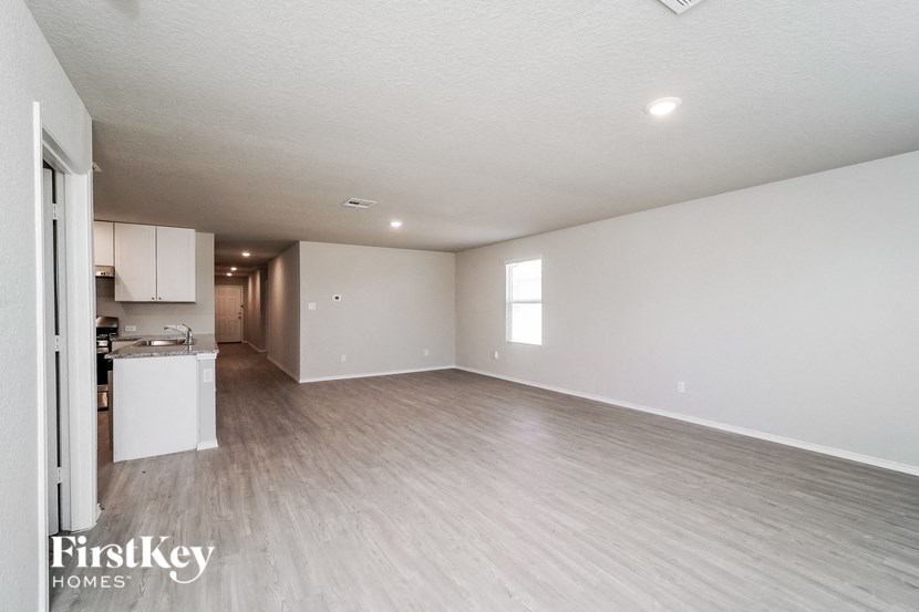 an empty living room and kitchen with white walls and wood flooring