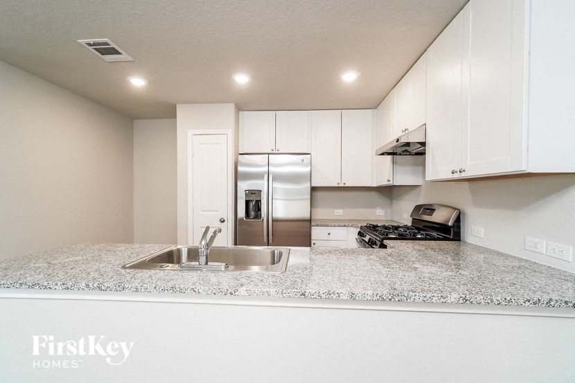 a kitchen with white cabinets and a sink and a refrigerator