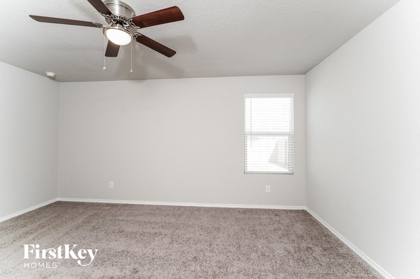 a bedroom with a ceiling fan and a carpet