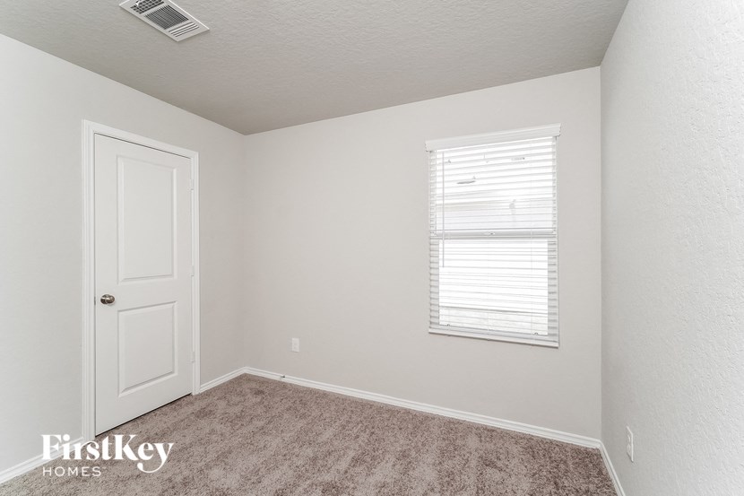 a bedroom with white walls and a white door and a window
