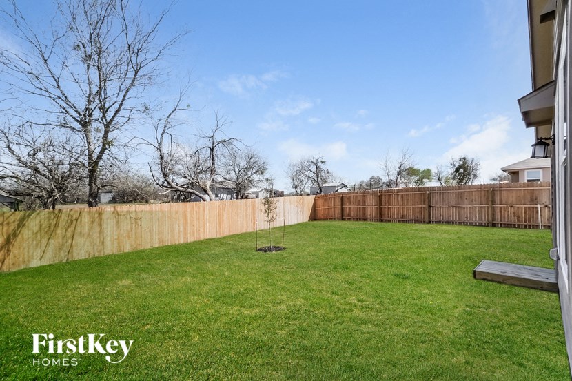 a backyard with a wooden fence and a green lawn