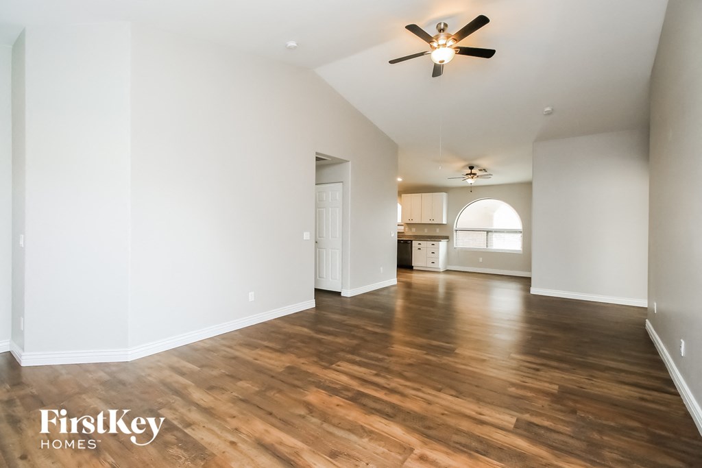 A spacious room with wooden floors and a ceiling fan.