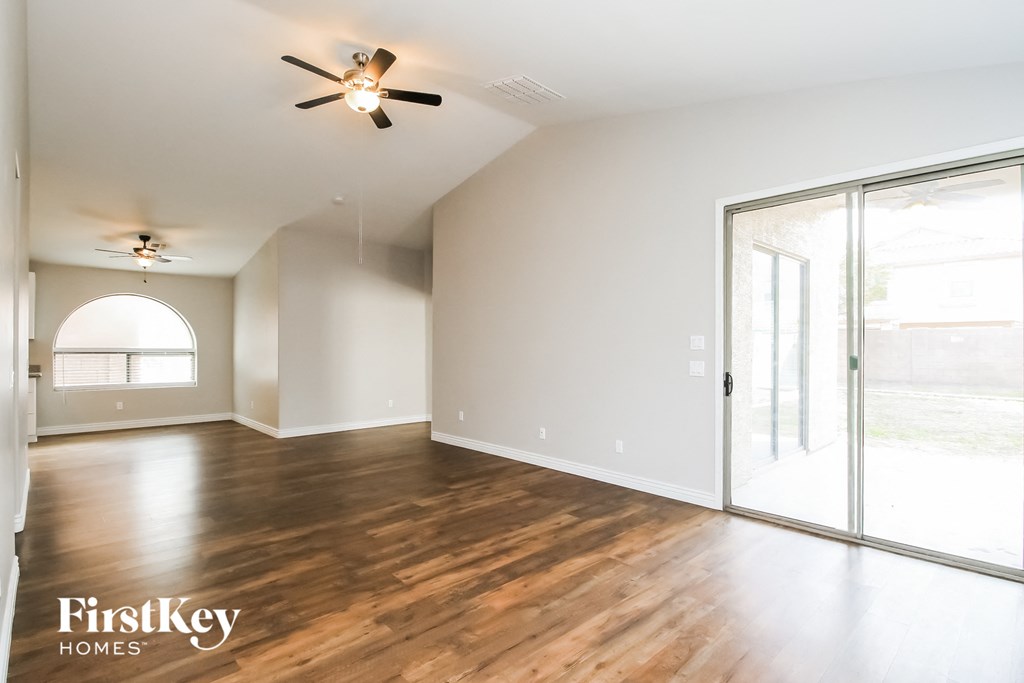 A spacious room with wooden floors and a ceiling fan.