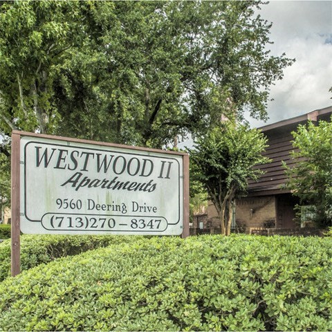 a sign for westwood ii apartments in front of a house
