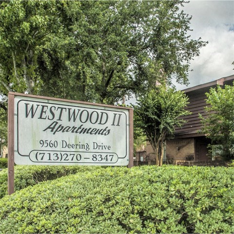 a sign for westwood ii apartments in front of a house