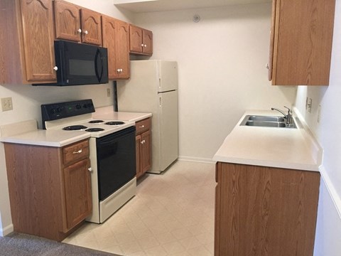 an empty kitchen with a stove refrigerator and sink