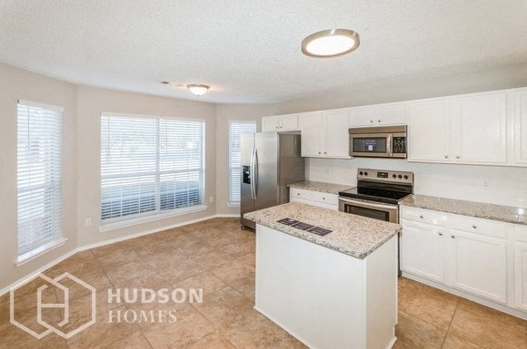 an empty kitchen with white cabinets and a granite counter top