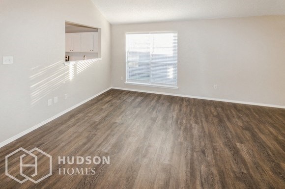 the living room of an apartment with wood flooring and a window