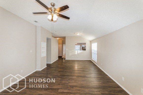 the living room is spacious and has a ceiling fan
