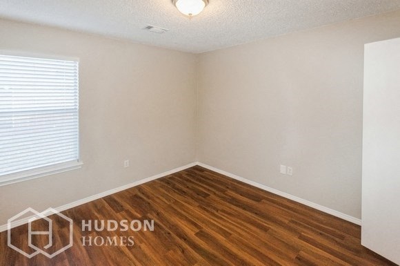 a bedroom with wood flooring and a window