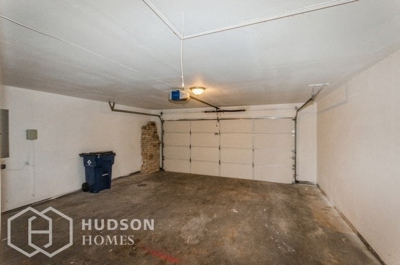 a garage with a white wall and a trash can in it