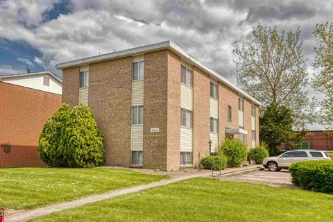 A brick apartment building with a green lawn in front.