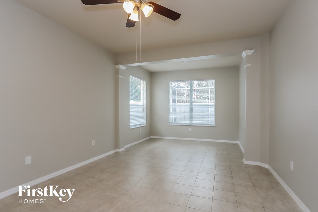 an empty living room with a ceiling fan and a window